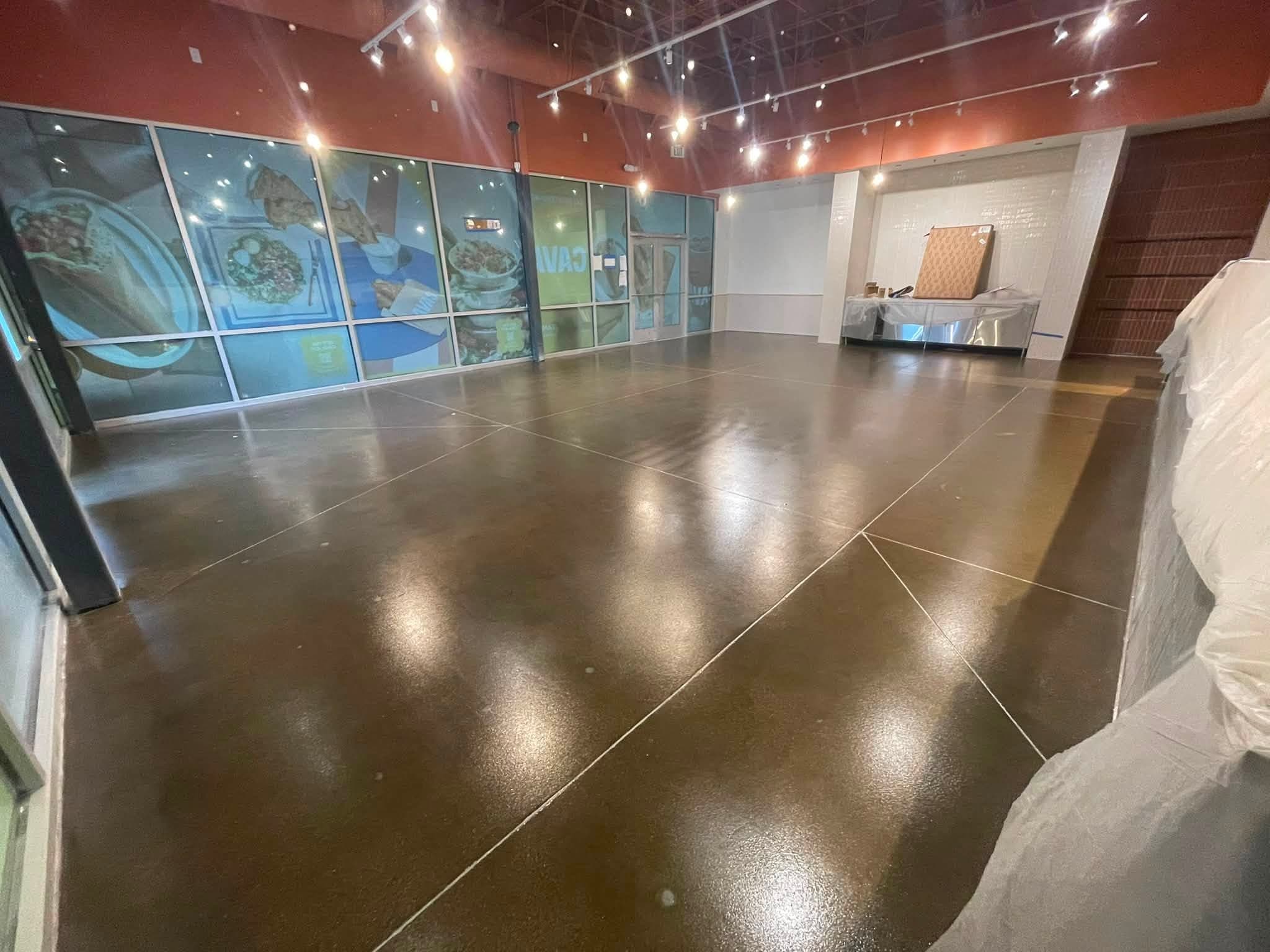 The same dining room with a glossy sealed concrete floor under track lighting