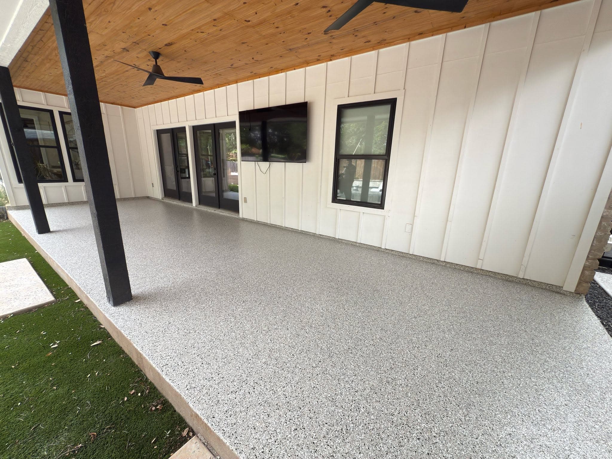 Finished gray flake floor on a covered porch of a white farmhouse-style home