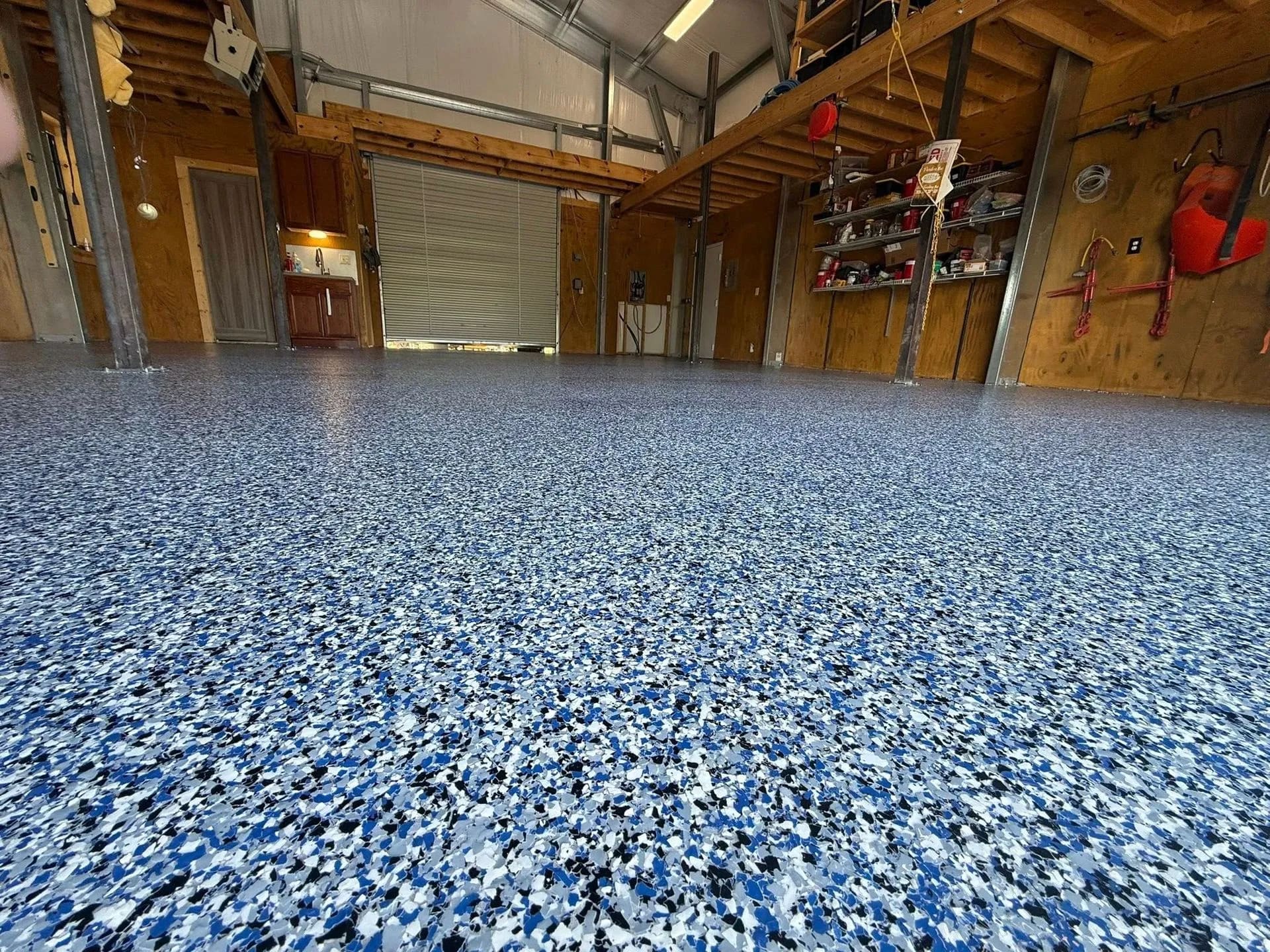 Wood-frame shop with a mezzanine loft and a blue, black and white flake floor