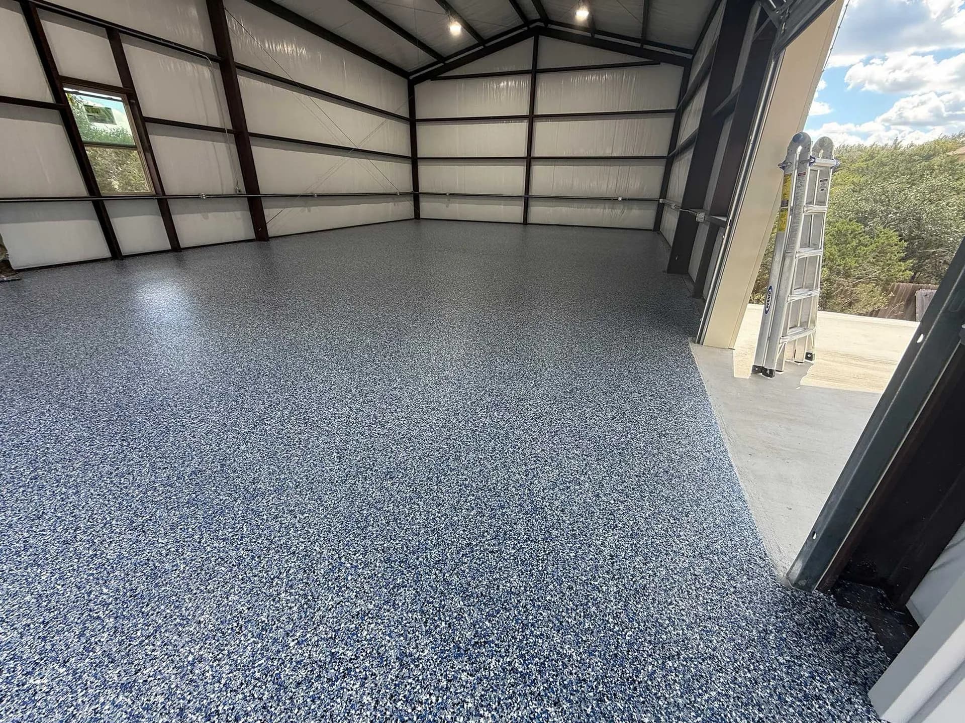 Metal shop building with a blue flake floor and exposed trusses