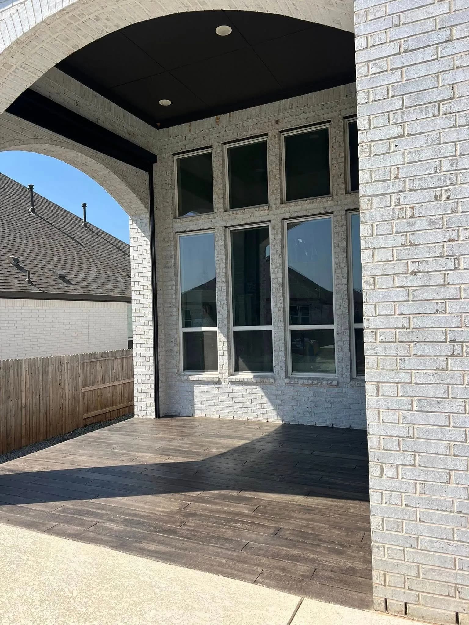 Dark wood-look stamped concrete floor on a covered stone porch