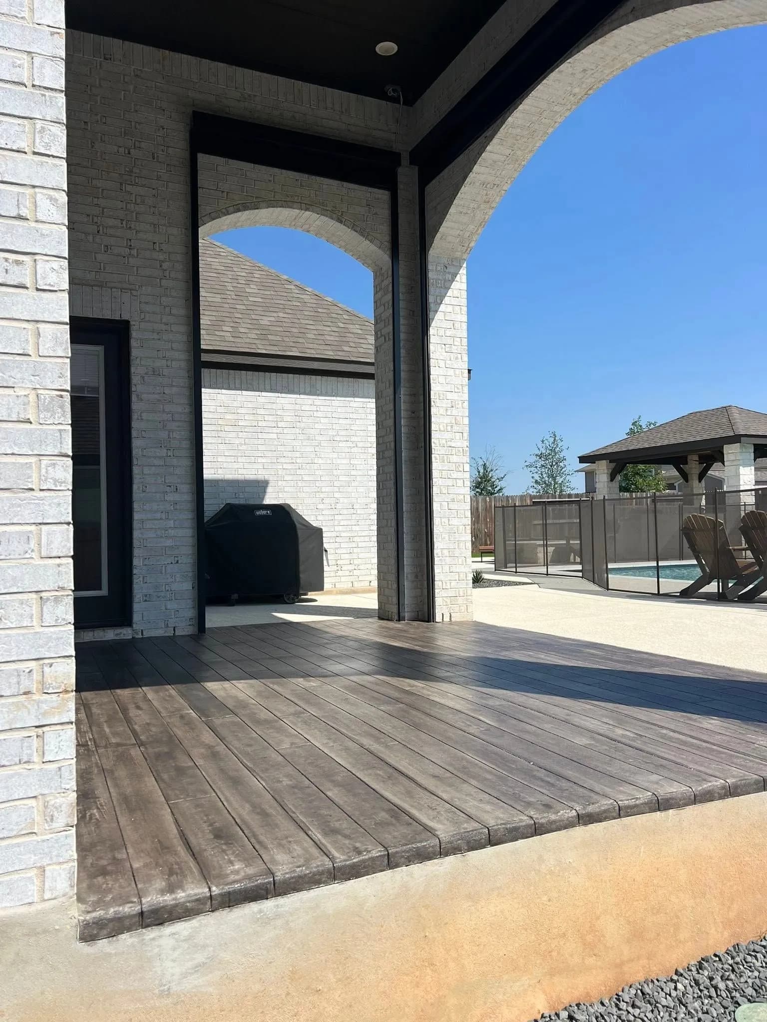 Wood-look concrete floor on a covered patio, pool and gazebo beyond