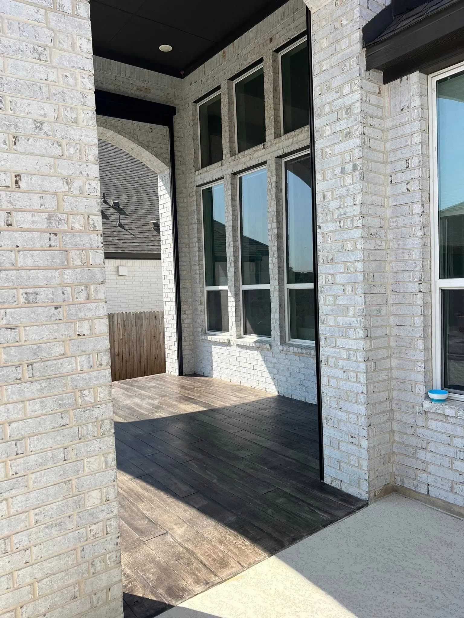 Wood-look stained concrete porch with arched brick columns